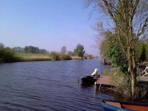 a river with two boats parked next to a dock at Holiday Home Zoutkamp near Lauwersmeer in Zoutkamp