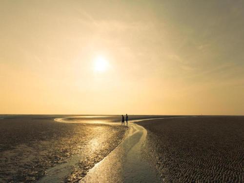 two people walking on the beach at sunset at Holiday Home Zoutkamp near Lauwersmeer in Zoutkamp