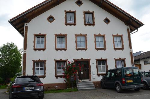 a white house with windows and a car parked in front at Die Dirndlkönigin in Grünenbach