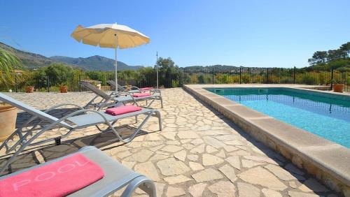 Un grupo de sillas y una sombrilla junto a una piscina. en Ferienhaus in Selva mit Gepflegtem Garten, en Selva
