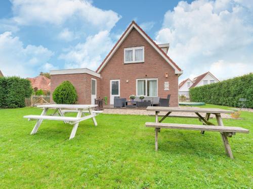 two picnic tables in front of a house at Holiday Home in Zeewolde near Forest in Zeewolde