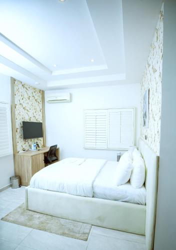 a white bedroom with a bed and a television at Tranquil Oasis Hotel in Ilado