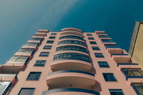 a tall pink building with a blue sky in the background at Wicalia ShortStays in Mem Martins