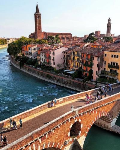 a group of people walking on a bridge over a river at FORTUNA ORO Luxury Stay in Verona