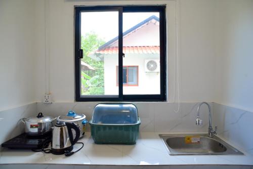 Una encimera de cocina con un fregadero y una ventana. en Densy Khmer Homestay, en Siem Reap