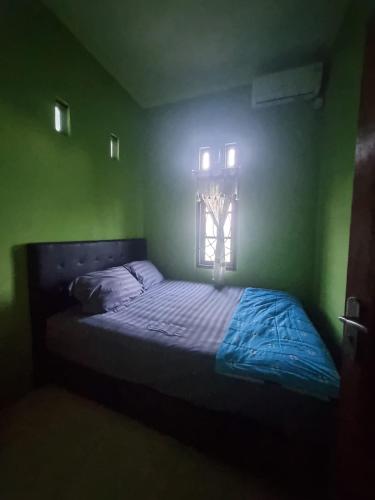 a bed in a green room with a window at Homestay Barokah in Magelang