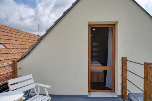 a white house with a wooden door and a bench at House Big Win Mělník in Mlazice