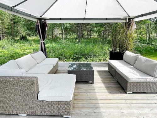 a patio with two couches and an umbrella at 10 person holiday home in KATTHAMMARSVIK in Katthammarsvik