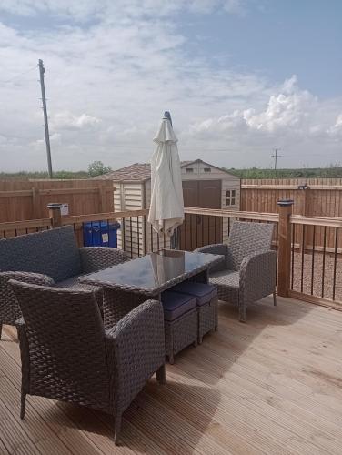 a patio with a table and chairs and an umbrella at Lapwing Lodge, Howdales in Louth
