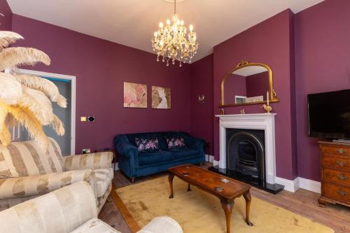 a living room with purple walls and a blue couch at Luxury Georgian home & garden by the sea, 6 guests in Bognor Regis