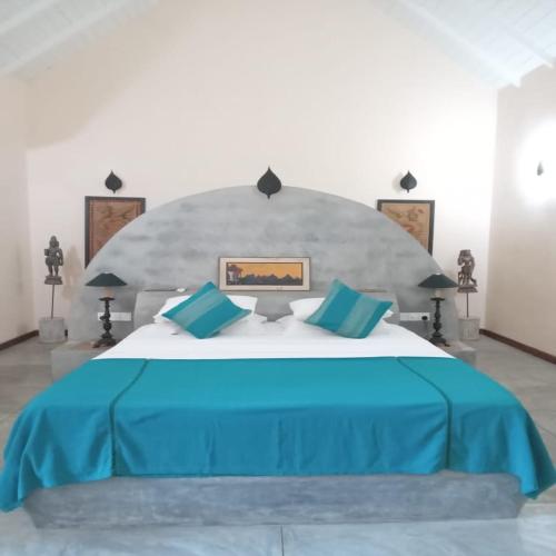 a bedroom with a large bed with a blue blanket at Shangri-Lanka Village in Tissamaharama