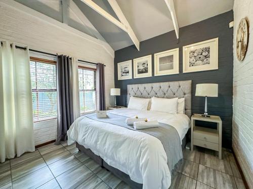 a bedroom with a large white bed and two windows at 3 on Pine, Luxury Home[WiFi,DSTV,Parking incl] in George