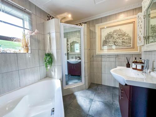 a bathroom with a tub and a sink at 3 on Pine, Luxury Home[WiFi,DSTV,Parking incl] in George