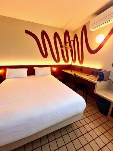 a hotel room with a large bed and a sign on the wall at The Originals City, Hôtel du Phare, Bordeaux Mérignac in Mérignac