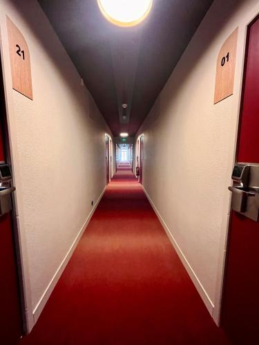 a long hallway with a red carpet and a ceiling at The Originals City, Hôtel du Phare, Bordeaux Mérignac in Mérignac