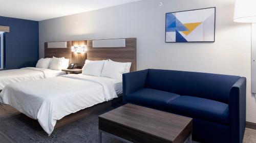 a hotel room with two beds and a blue chair at Holiday Inn Express Hotel & Suites Waterloo - St. Jacobs Area by IHG in Waterloo