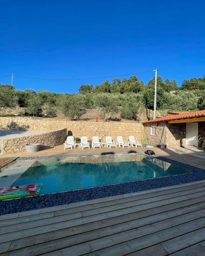 a swimming pool with white chairs and a deck at Gabriela Olival turismo