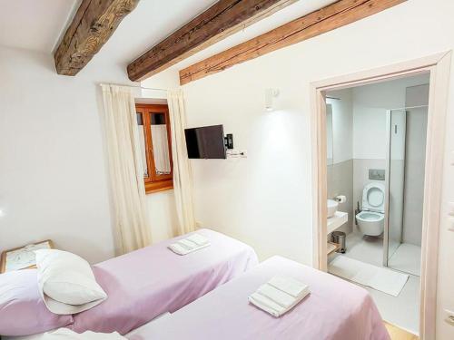 two beds in a white room with a bathroom at Home Dren in Prepotto