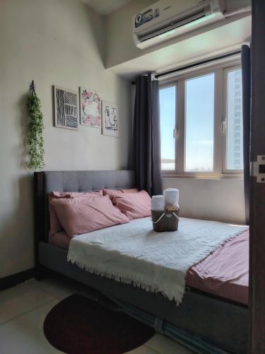 una camera da letto con un letto con lenzuola rosa e una finestra di CozyStay by MA Condotel-Coast Residences a Manila