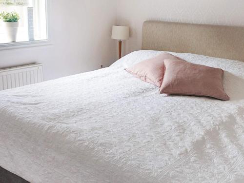 a white bed with a pink pillow on it at Rustic Retreat in Smaland-By Traum in Väckelsång