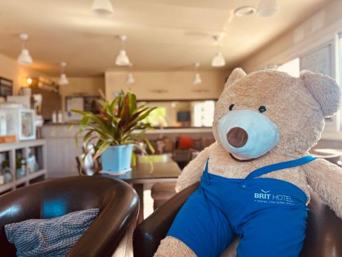 a teddy bear sitting in a chair with a mask on at BRIT HOTEL Lannion-Perros Guirec in Lannion
