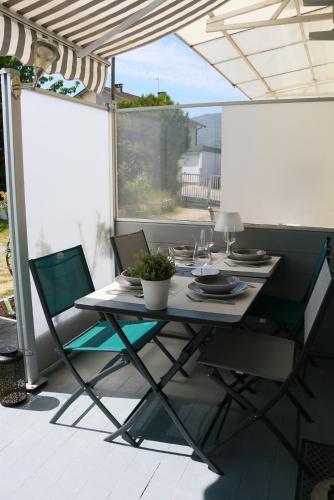 une table et des chaises sur une terrasse avec une fenêtre dans l'établissement La Brison-T'Inn, à Grésine