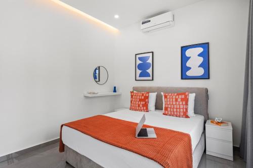 a white bedroom with a bed with orange pillows at Theon Urban Suites by Nomads in Paphos City