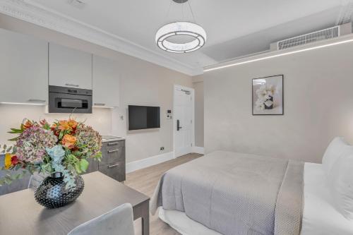 a room with a bed and a table with a vase of flowers at Cleveland Residences Bloomsbury in London