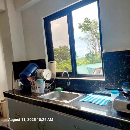 a kitchen counter with a sink and a window at Charming 2BR Apartment with Balcony and Mountain View - Logan's Transient Apartment 2 in Baguio