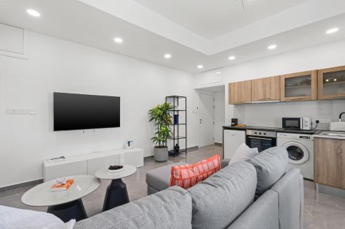 a living room with a gray couch and a kitchen at Theon Urban Suites by Nomads in Paphos City