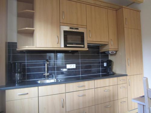 a kitchen with wooden cabinets and a microwave at Holiday Home in Well near Maasduinen Park in Knikkerdorp