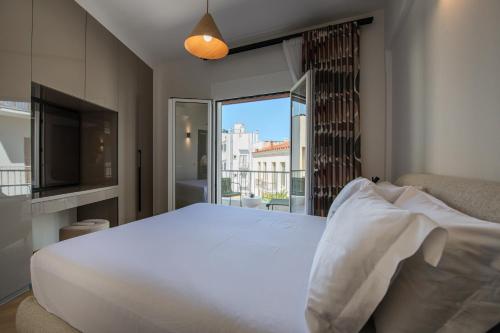 a bedroom with a large white bed and a window at Porto Searene in Nafplio