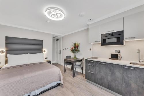 a bedroom with a large bed and a kitchen at Cleveland Residences Bloomsbury in London