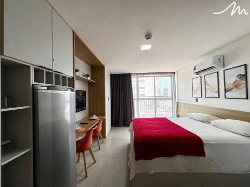 a bedroom with a bed and a table and a refrigerator at Get By Side - Jardim Oceania in Tambaú