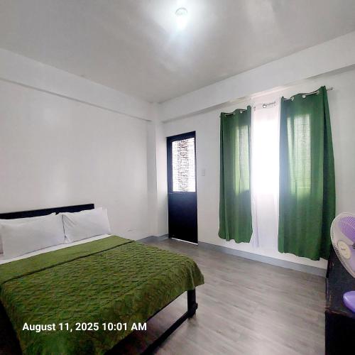 a bedroom with a bed with green sheets and a window at Charming 2BR Apartment with Balcony and Mountain View - Logan's Transient Apartment 2 in Baguio
