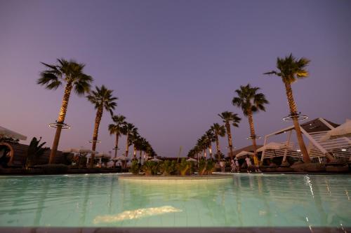 a swimming pool with palm trees in a resort at Shades Beach Club in Jeddah