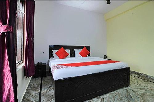 a bedroom with a bed with red pillows and a window at HoTEL MEHRAZ in Haldwāni