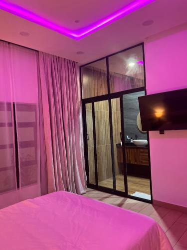 a bedroom with a pink lighting and a large window at Villa de l'atlantique in Abomey-Calavi