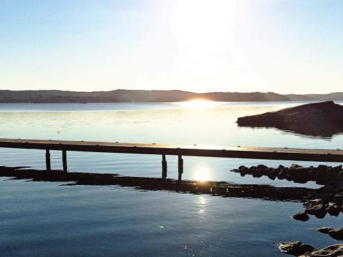 a dock on a body of water with the sun setting at 5 person holiday home in VAREKIL in Varekil