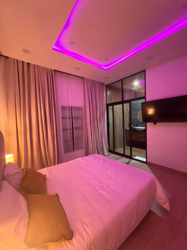 a bedroom with a white bed with a purple lighting at Villa de l'atlantique in Abomey-Calavi