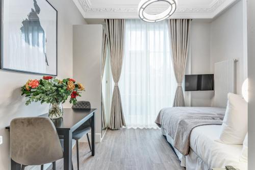 a bedroom with a bed and a desk with a vase of flowers at Cleveland Residences Bloomsbury in London