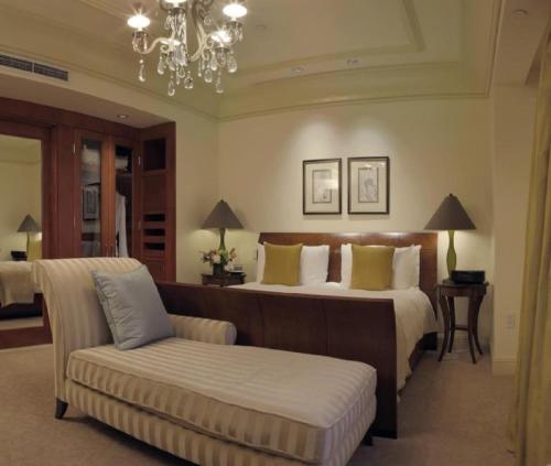 a bedroom with a bed and a couch and a chandelier at Hotel TuLiP Inn Near Delhi Airport in New Delhi