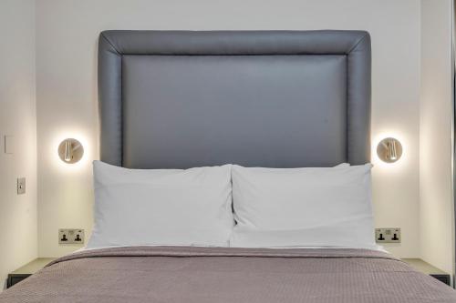 a bed with a gray headboard and two pillows at Cleveland Residences Bloomsbury in London