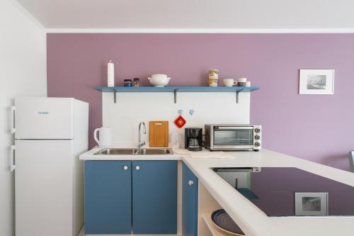 a small kitchen with blue cabinets and a white refrigerator at The Green Turtle Eco Lodge in Willemstad