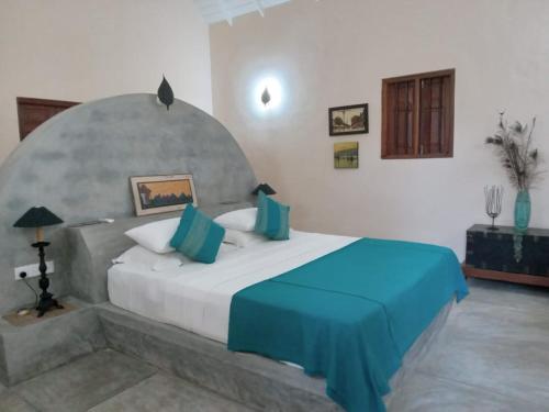 a bedroom with a large bed with a blue blanket at Shangri-Lanka Village in Tissamaharama