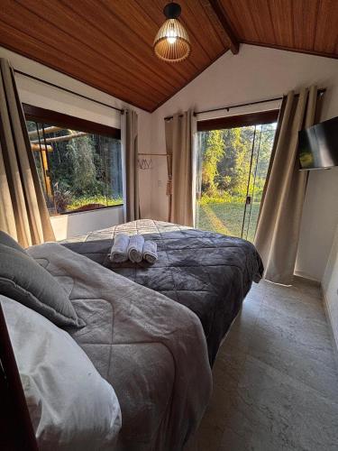 a bedroom with two beds and a large window at Casa di Pedra com linda vista para natureza - Miguel Pereira in Miguel Pereira