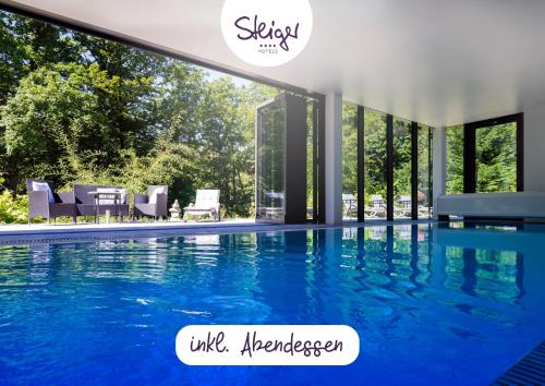 a swimming pool with blue water in a house at Parkhotel Hohnstein by STEIGER Hotels in Hohnstein