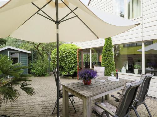 a wooden table with an umbrella on a patio at Holiday Home in Noordwijkerhout by Forest & Lake in Noordwijkerhout