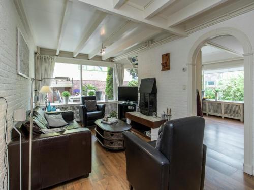 a living room with leather furniture and an archway at Holiday Home in Noordwijkerhout by Forest & Lake in Noordwijkerhout