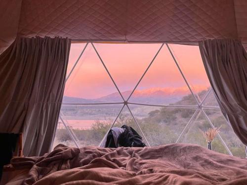 a bed with a view of the mountains through a window at El Nido Domos in Mendoza